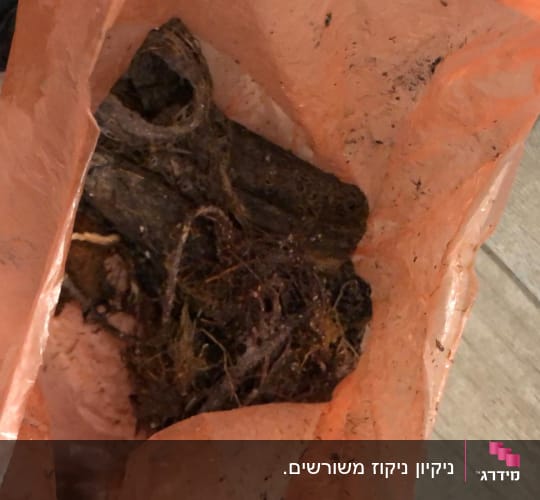 שקית כתומה עם פסולת סתימה שהוצאה מצינור